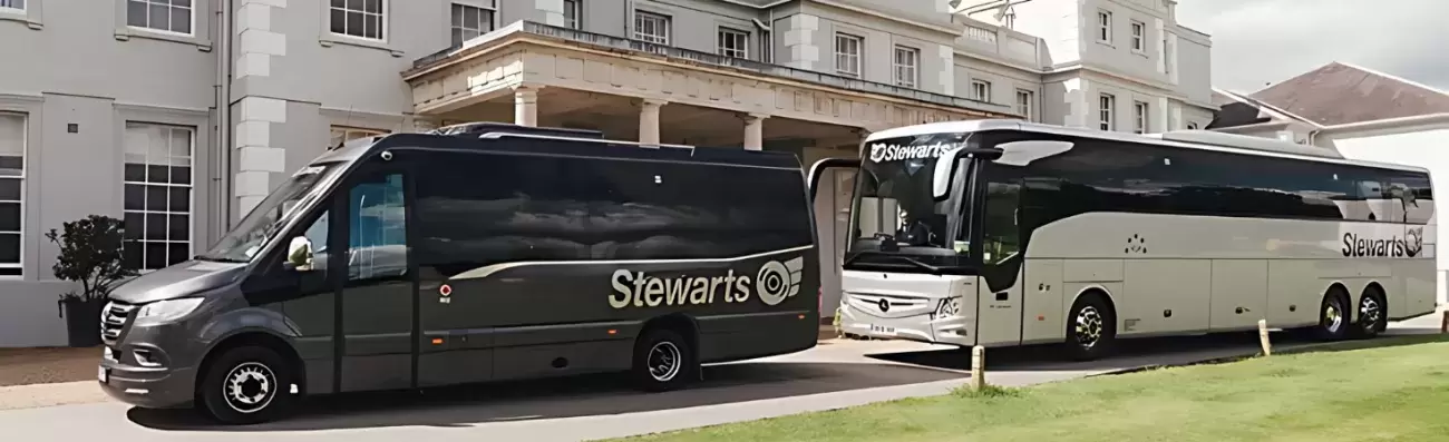 Two Stewarts vehicles—a black minibus and a silver coach - parked outside a hotel building.